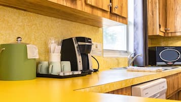 A kitchen with wooden cabinets, a coffee maker, and a dishwasher.