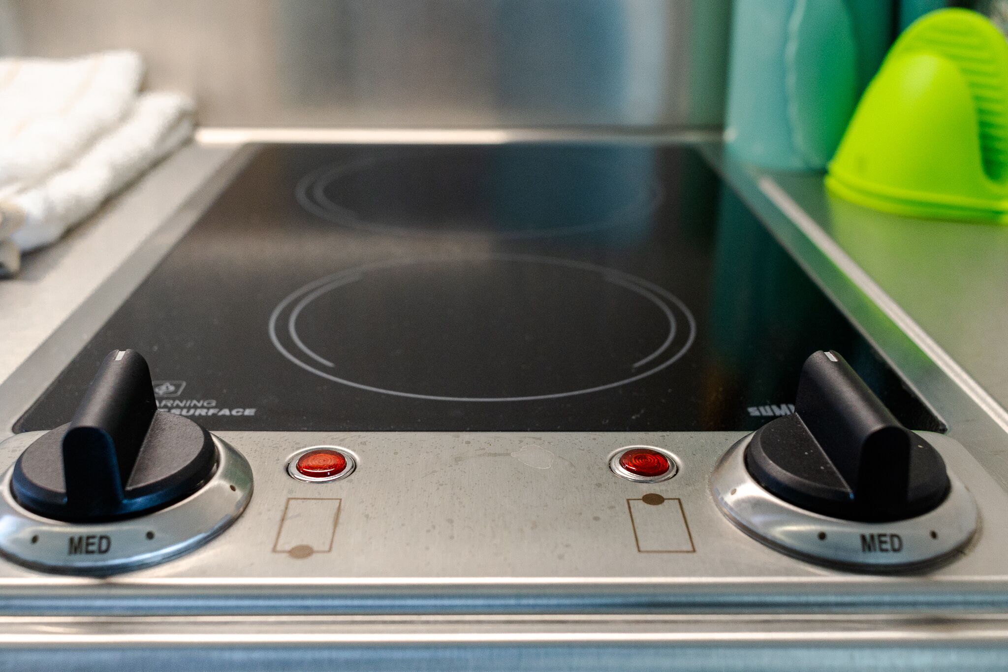 A kitchen with a black induction cooktop, two control knobs, and two red indicator lights.