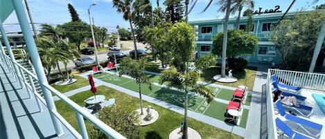 Un hotel con piscina, zona de estar al aire libre y palmeras.