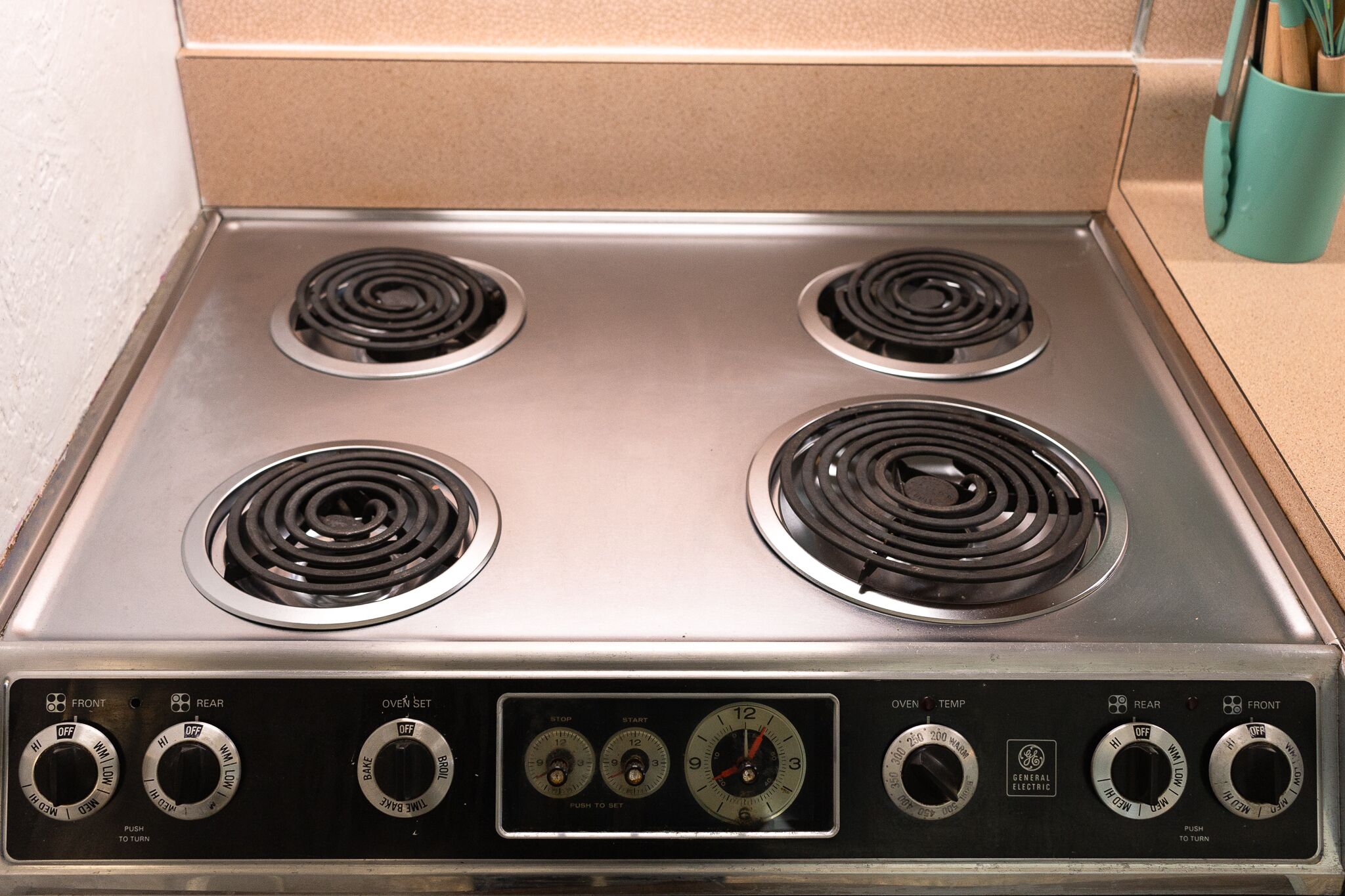 A four-burner stove with control knobs and a digital display.