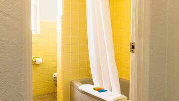 A bathroom with yellow tiles, a white toilet, and a bathtub with a white shower curtain.