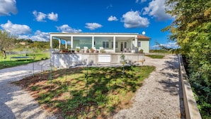 A modern house with a covered patio, a gravel driveway, and a garden with potted plants. - Stunning home in Zminj (Zminj)