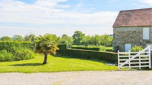Een gebouw van steen met een rode dakbedekking, een witte hek en een grindpad er naartoe.