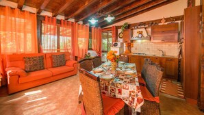 A cozy living room with a sofa, dining table, and kitchen area with wooden cabinets and a tiled backsplash. - Lovely home in Menfi with WiFi (Menfi)
