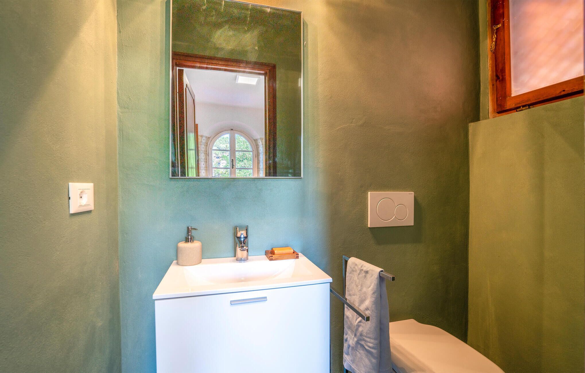 Un baño con un lavabo blanco, un espejo y un perchero para toallas.