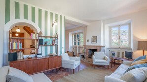 A living room with a fireplace, bookshelves, and a cozy seating area. - 3 bedroom stunning home in Marciana (Marciana)