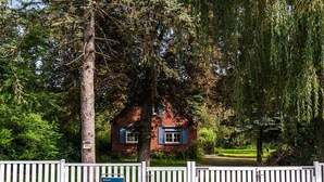 A small brick house with a white fence and a sign indicating it is managed by NOVASOL.