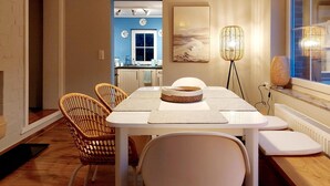 A dining area with a white table, wicker chairs, and a woven basket on the table.