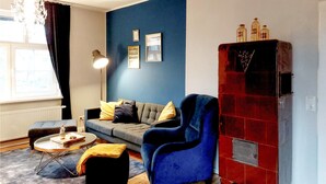 A living room with a blue sofa, a black armchair, a round coffee table, and a red cabinet.