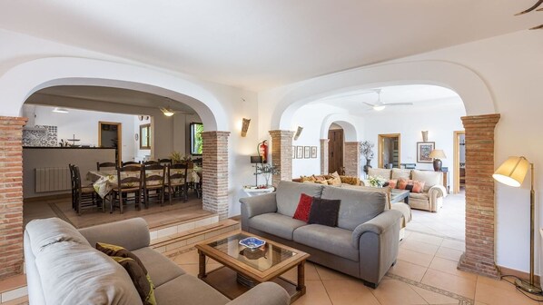 A spacious living area with a sofa, coffee table, and a dining area in the background.