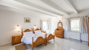 Une chambre à coucher avec un lit en bois, des tables de chevet, une commode et une fenêtre avec des rideaux.