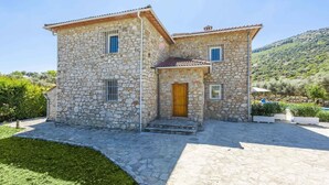 Une maison en pierre avec une porte en bois, un petit porche et une vue sur un paysage verdoyant.