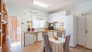 Une cuisine compacte avec des meubles blancs, un petit coin repas doté d’une table et un lave-vaisselle.