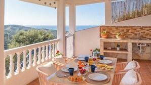 Un balcon avec une table à manger dressée pour le petit-déjeuner, une cheminée en pierre et une vue magnifique.