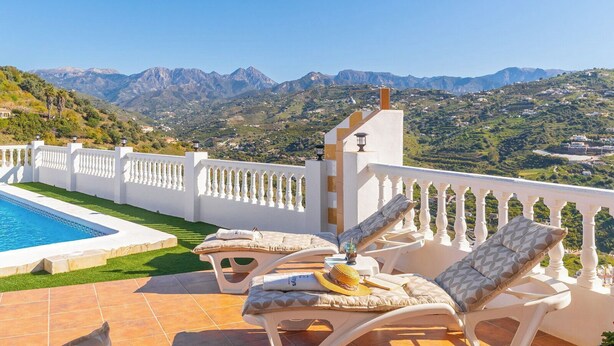 Un espace aménagé au bord de la piscine, avec des chaises longues, une piscine et une vue sur les montagnes.