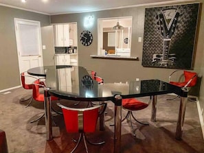 A dining area with a glass table and red chairs, a kitchen in the background, and a clock on the wall. - Right in Nashville, One of the last standing farms (Nashville)
