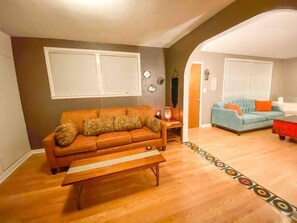 A living room with a brown sofa, a blue sofa, and a wooden coffee table. - Right in Nashville, One of the last standing farms (Nashville)