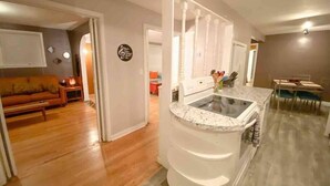 A modern kitchen with a built-in stove, white cabinets, and a marble countertop. - Right in Nashville, One of the last standing farms (Nashville)