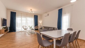 A modern living room with a dining table, grey chairs, a sofa, and a TV. - Pet friendly home in Radasinovci (Radasinovci)