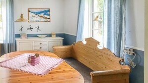 A cozy room with a wooden bench, a dining table with a pink placemat, a white cabinet with kitchen items, and a painting of a snowy landscape. - 2 bedroom cozy apartment in Boliden (Boliden)