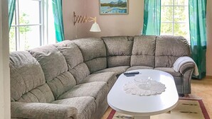 A corner living room with a beige sectional sofa, a white coffee table, and a painting on the wall. - 2 bedroom cozy apartment in Boliden (Boliden)