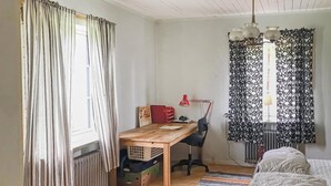 A small, tidy room with a wooden desk, a chair, a radiator, a bed, and a window with curtains. - 2 bedroom cozy apartment in Boliden (Boliden)