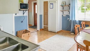 A kitchen with a sink, a microwave, a refrigerator, wooden cabinets, and a dining area with a table and chairs. - 2 bedroom cozy apartment in Boliden (Boliden)
