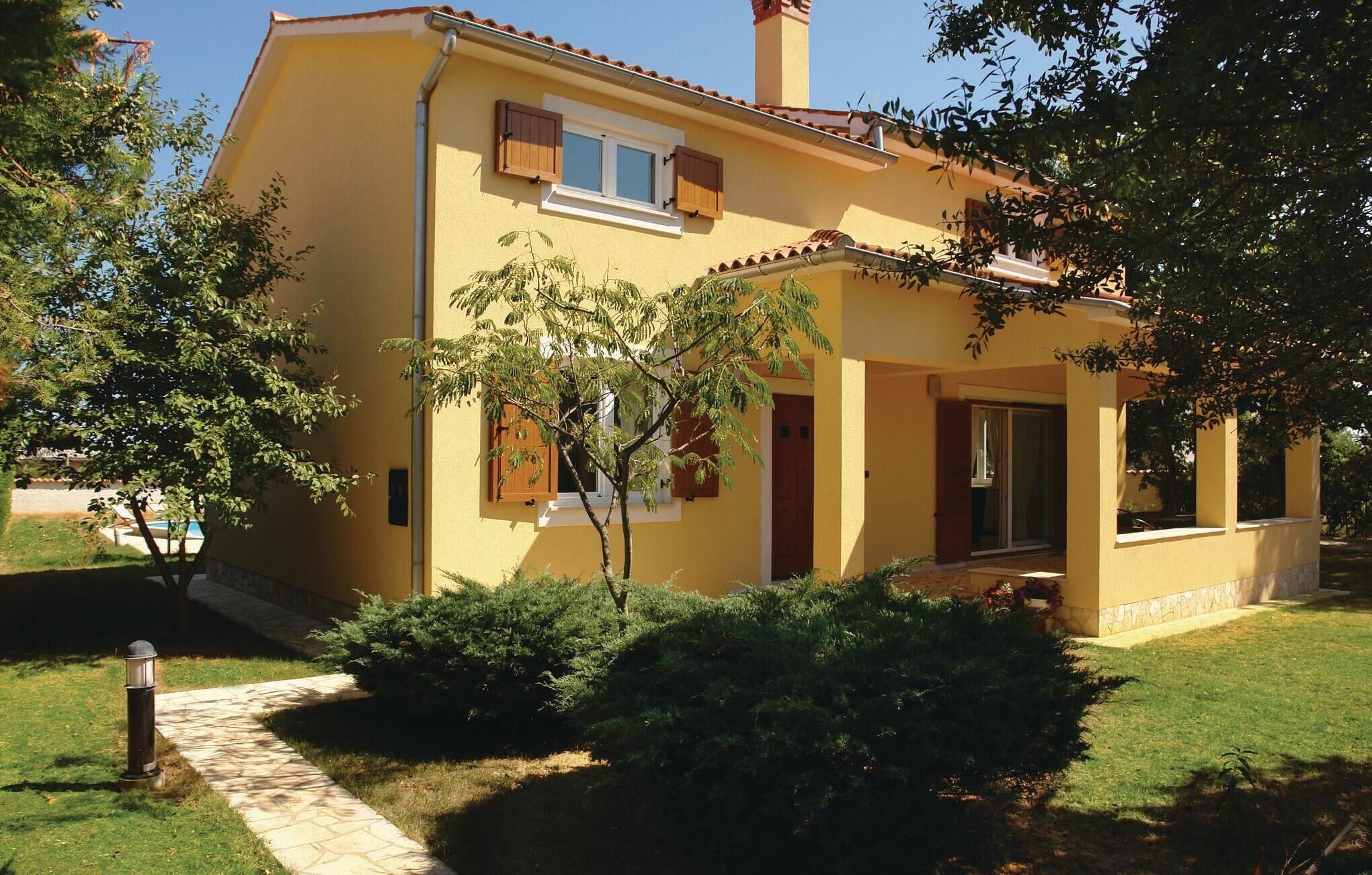 A yellow building with a tiled roof, a chimney, and a small porch with a door.