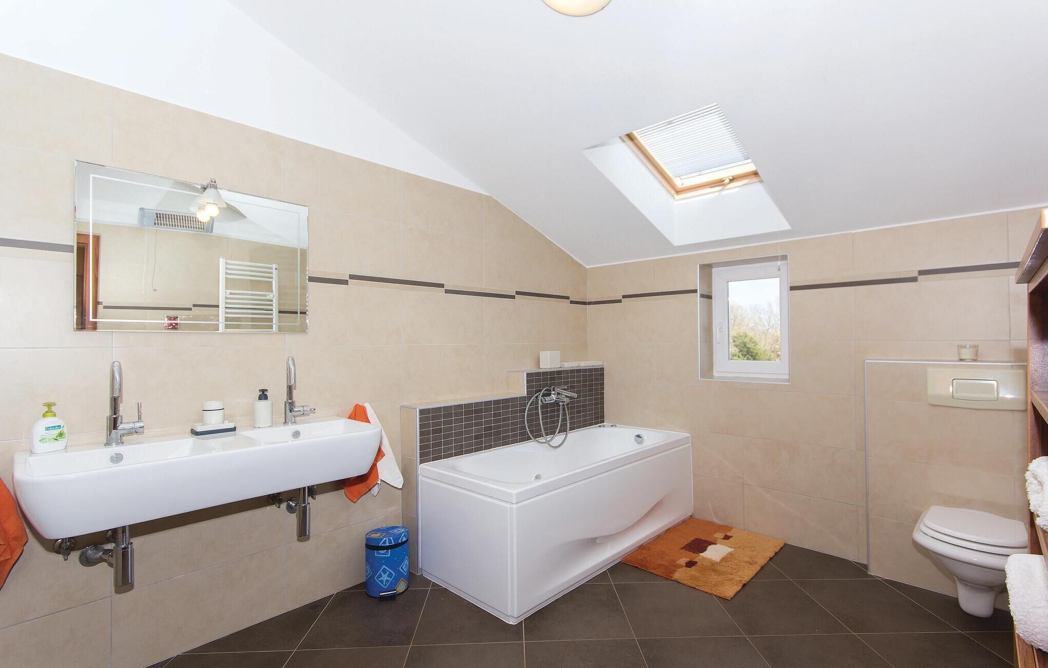Een moderne badkamer met dakraam, een badkuip, een wastafel en een toilet.