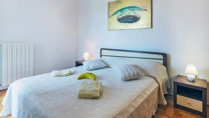 A neatly made bed with a patterned bedspread, a bedside lamp, and a wall-mounted painting. - Awesome apartment in Pula with WiFi (Pula)