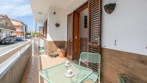 A balcony with a table and chairs, potted plants, and a wooden door.