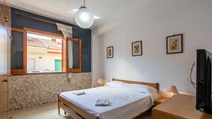 A bedroom with a bed, bedside lamps, a TV, and framed floral artwork on the wall.