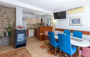 Une cuisine compacte avec un coin repas, un téléviseur fixé au mur et une cheminée.
