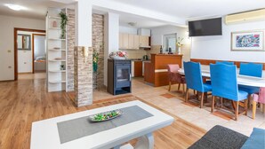 Een moderne woonruimte met een eethoek, keuken en een aan de muur bevestigde televisie.
