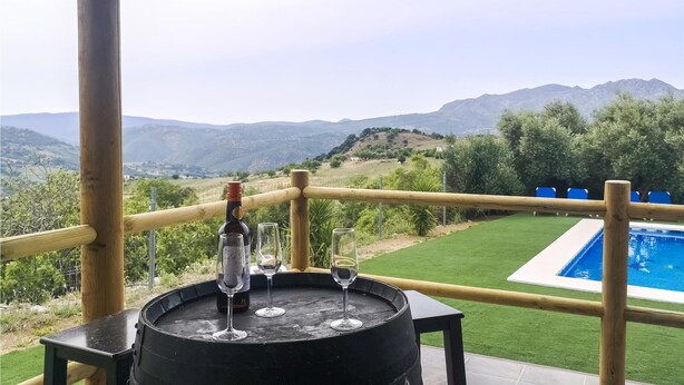 A table with a bottle and glasses, overlooking a pool and mountains. - Nice home in Algatocin (Algatocin)