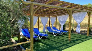A covered outdoor seating area with blue lounge chairs and white curtains. - Nice home in Algatocin (Algatocin)