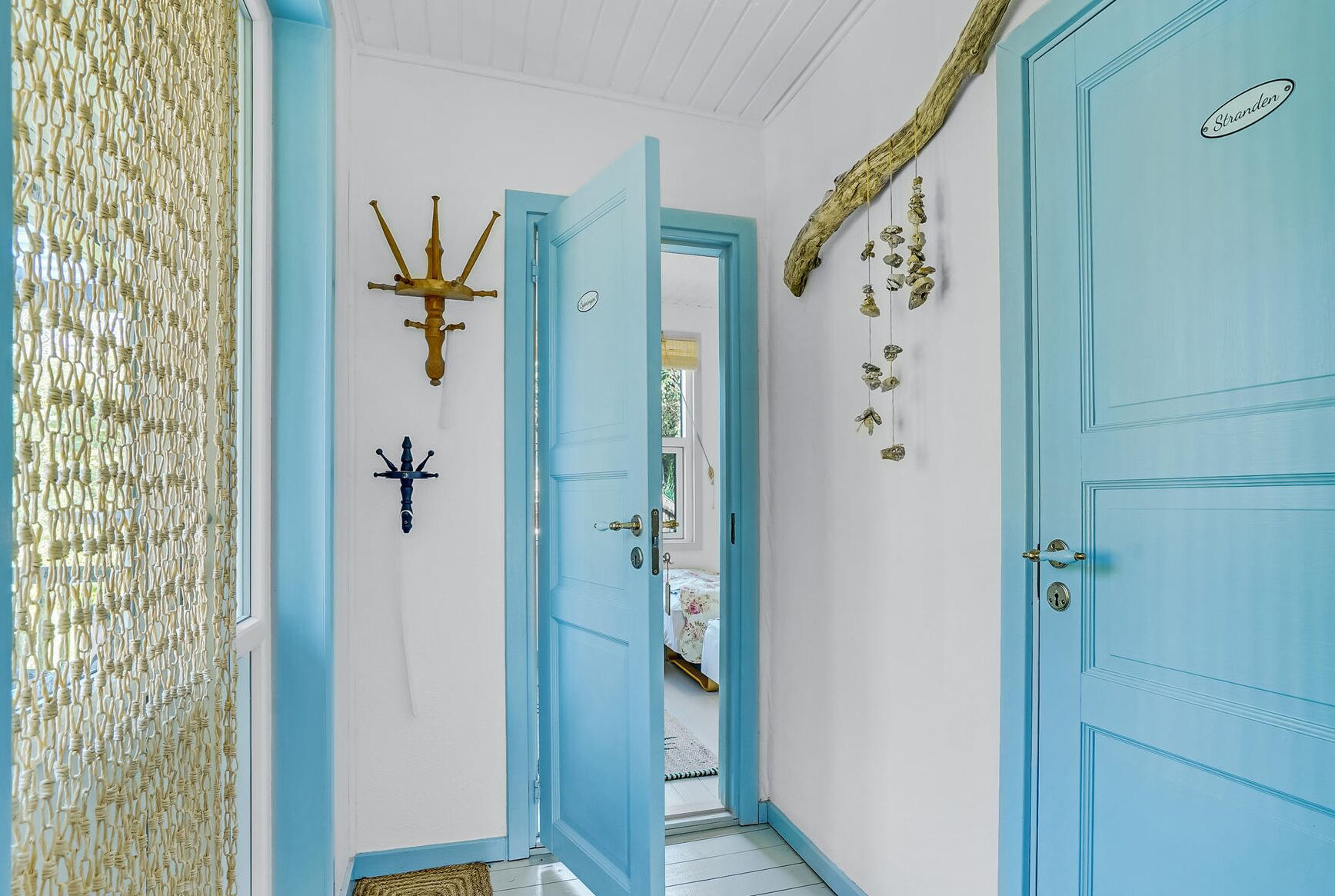 A hallway with a blue door, a decorative wall hanging, and a textured wall.