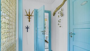 Un passadís amb una porta blava, un penjador decoratiu i una paret amb relleu.