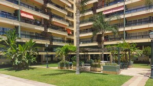 A multi-story hotel with balconies, a central courtyard with palm trees, and outdoor seating areas. - Nice apartment in Torremolinos with swimming pool (Torremolinos)