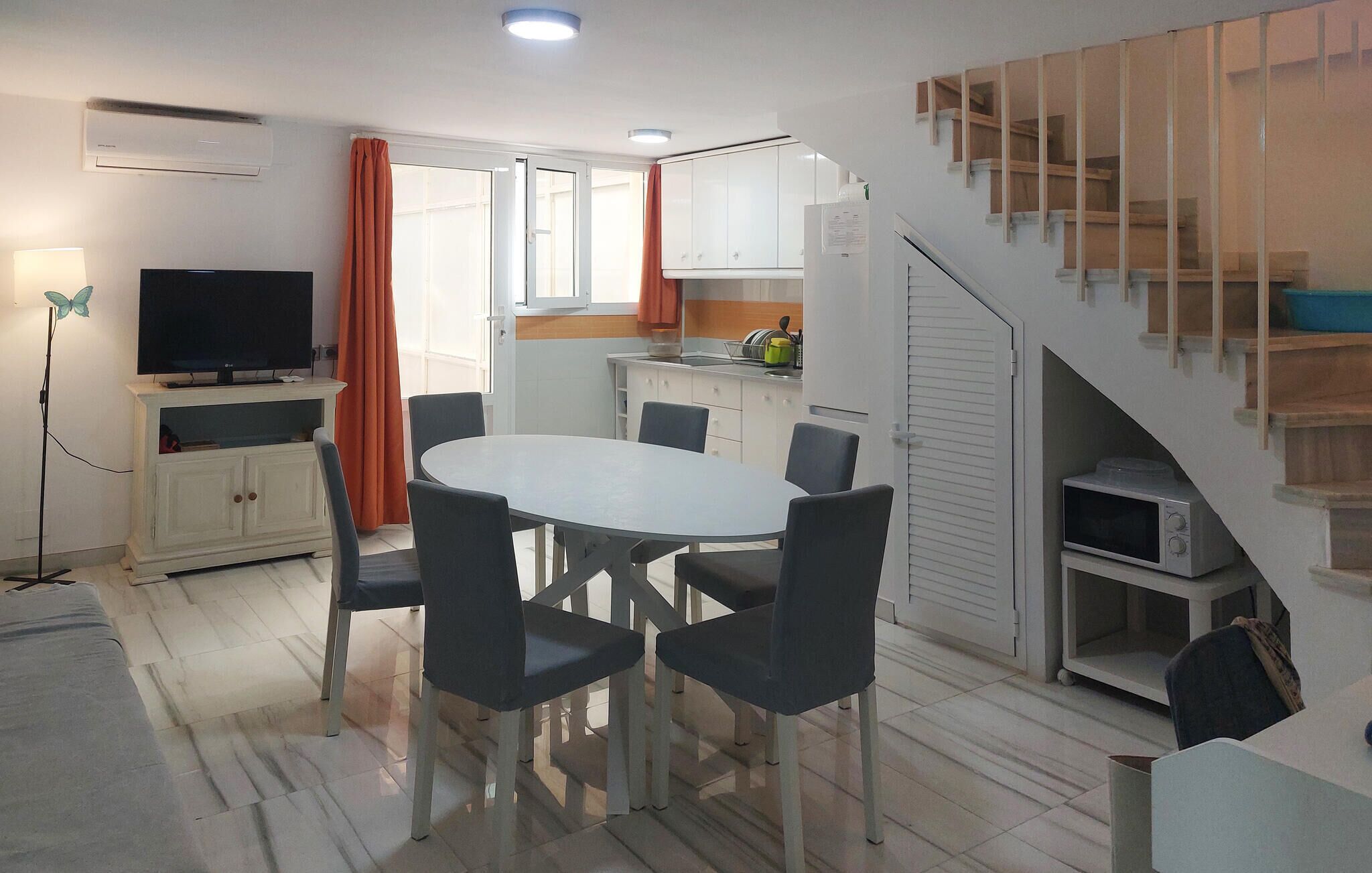 A compact living space with a dining area, kitchenette, and a staircase.