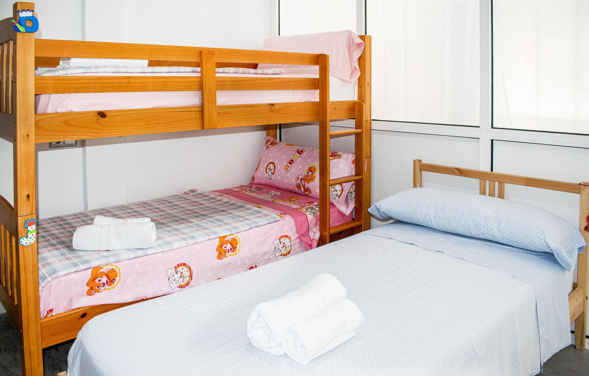 Une chambre avec un lit superposé, comportant deux lits, chacun recouvert d’une couette à motifs différents.