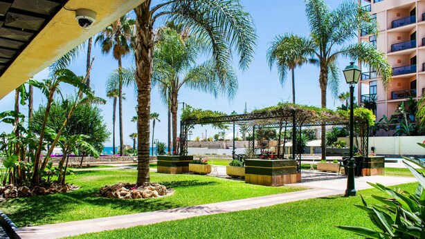 A well-maintained outdoor area with palm trees, a covered seating area, and a pathway. - Nice apartment in Torremolinos with swimming pool (Torremolinos)