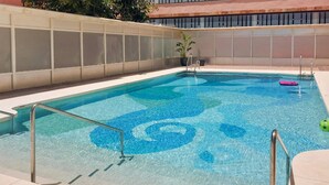 A rectangular swimming pool with clear blue water and a spiral pattern on the floor. There are two metal pool ladders on the left side. - Nice apartment in Torremolinos with swimming pool (Torremolinos)