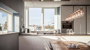 Une cuisine moderne avec une grande fenêtre, une table à manger en bois et un luminaire suspendu.