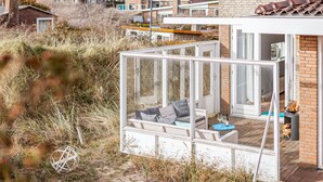 Une maison moderne dotée d’un porche vitré comprenant un canapé et une petite table.