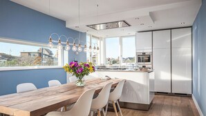 Une cuisine moderne avec des meubles blancs, une table à manger en bois et un vase rempli de fleurs.