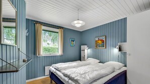 A bedroom with two beds, a window with curtains, a ceiling light, and artwork on the walls.