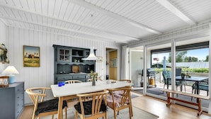 A dining area with a white table and chairs, a blue cabinet, and a view of the outdoors.