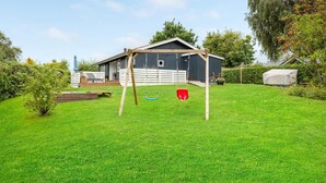 A house with a wooden swing set in the backyard.