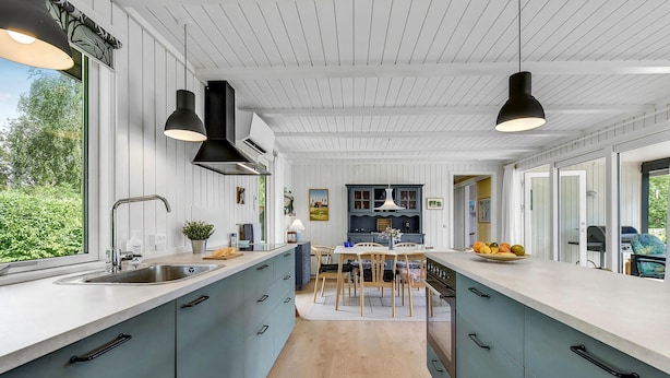 A modern kitchen with light blue cabinets, a central island, and pendant lighting.